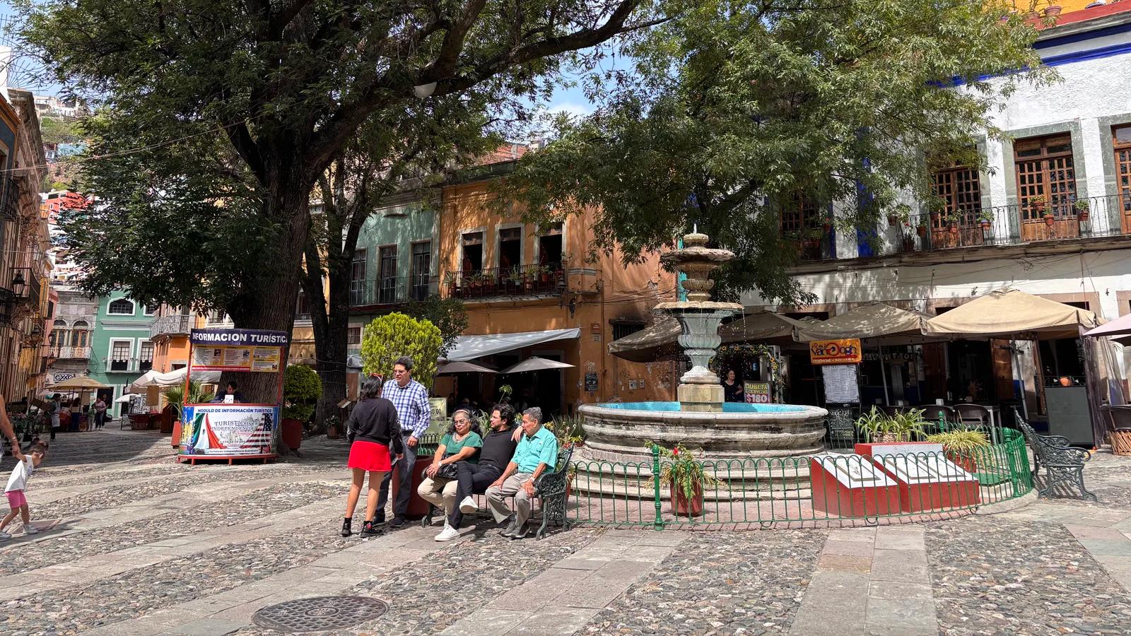 People relaxing in a leafy, colorful plaza in Guanajuato, Mexico